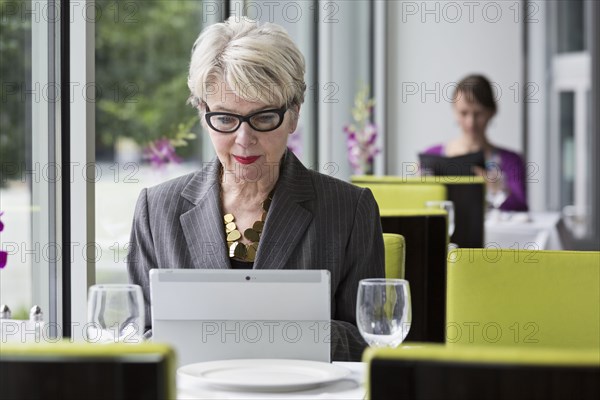 Caucasian businesswoman using tablet computer in restaurant