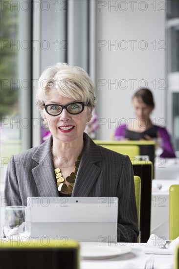Caucasian businesswoman using tablet computer in restaurant