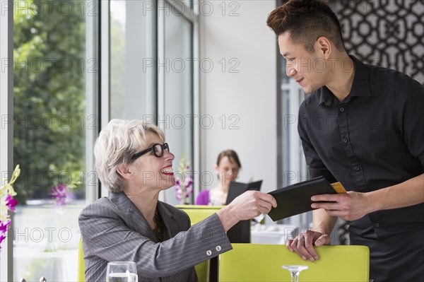 Businesswoman paying tab in restaurant