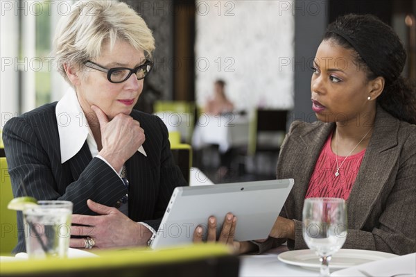 Businesswomen using tablet computer in restaurant