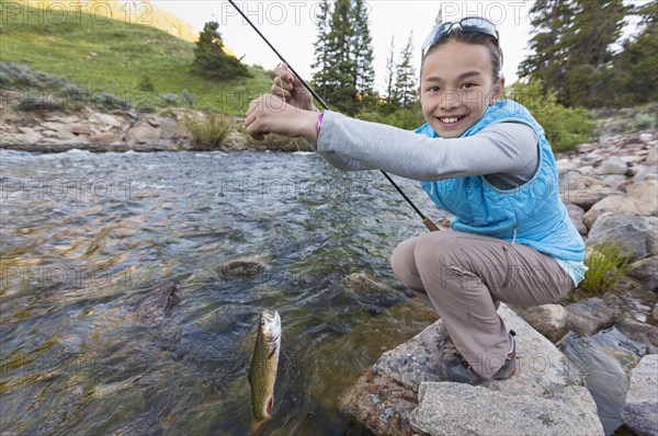Mixed race girl fishing in river