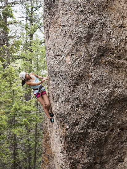 Mixed race girl climbing steep cliff