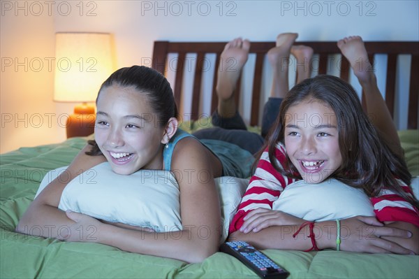 Mixed race sisters watching television on bed