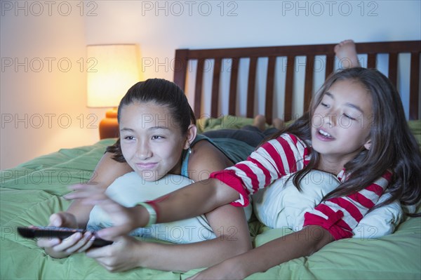 Mixed race sisters arguing about television on bed
