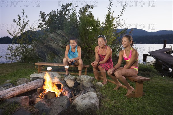 Mother and children roasting marshmallows over campfire