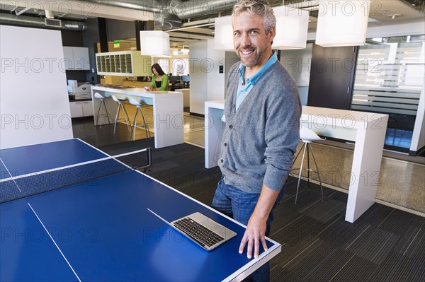 Businessman using laptop at table tennis table in office