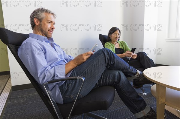 Business people using cell phones in office