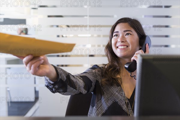 Mixed race businesswoman handing folder in office