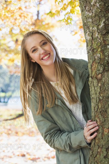 Caucasian woman peeking from behind tree