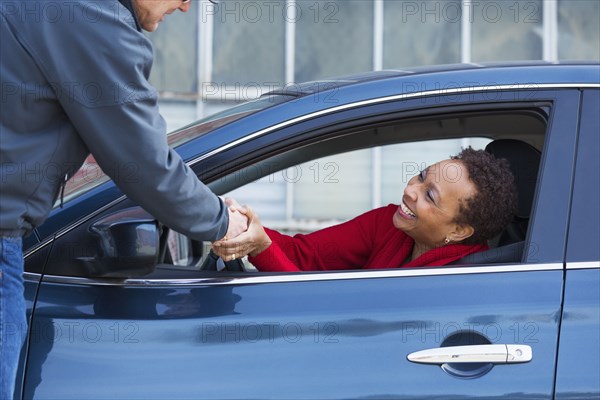 Friends shaking hands through car window