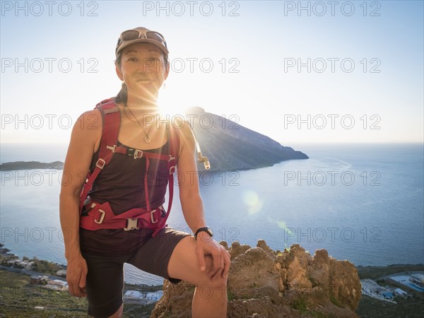 Japanese hiker standing on hilltop over ocean