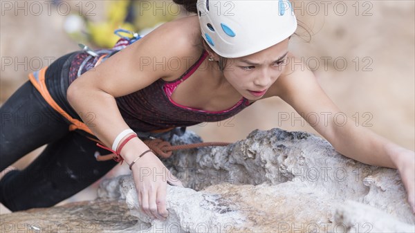 Mixed race girl climbing rock wall