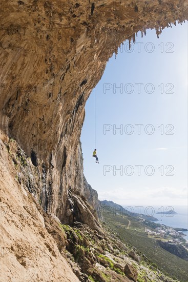 Caucasian climber hanging from cable on rock wall