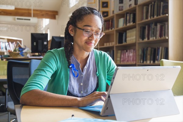 Mixed race student using digital tablet in library