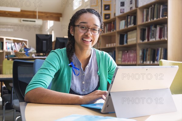 Mixed race student using digital tablet in library