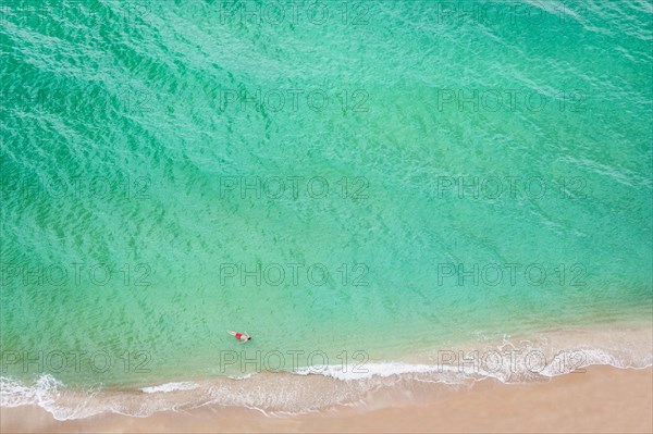Aerial view of Caucasian man swimming in ocean on beach