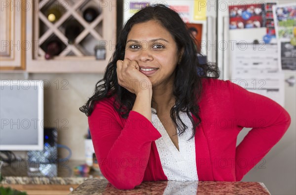 Indian woman leaning on kitchen counter