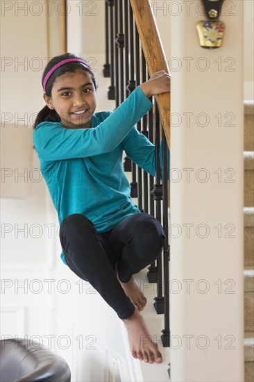 Indian girl climbing on staircase banister