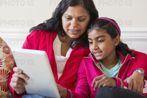 Indian mother and daughter using digital tablet