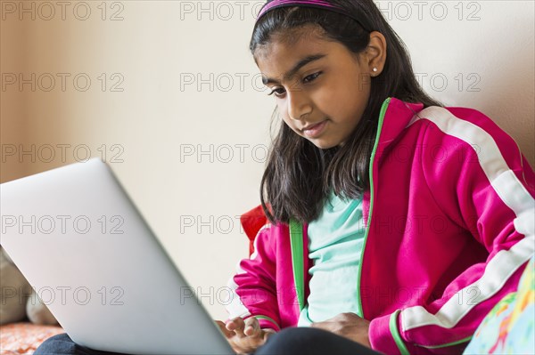 Indian girl using laptop on bed