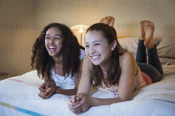 Teenage girls watching television on bed