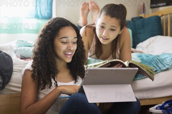 Teenage girls using digital tablet on bed