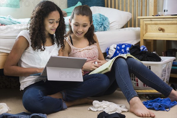 Teenage girls using digital tablet in bedroom