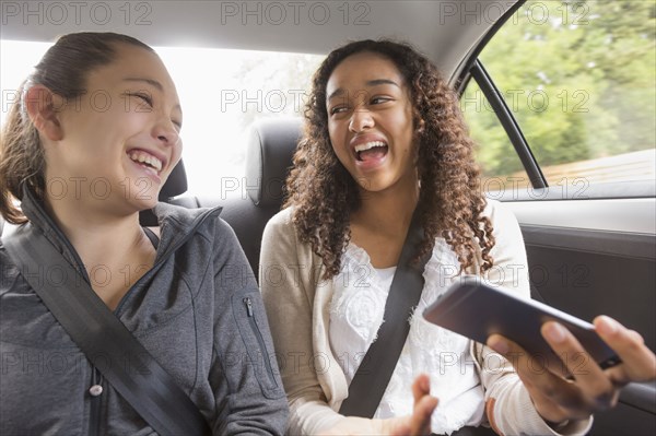 Teenage girls using cell phone in car back seat