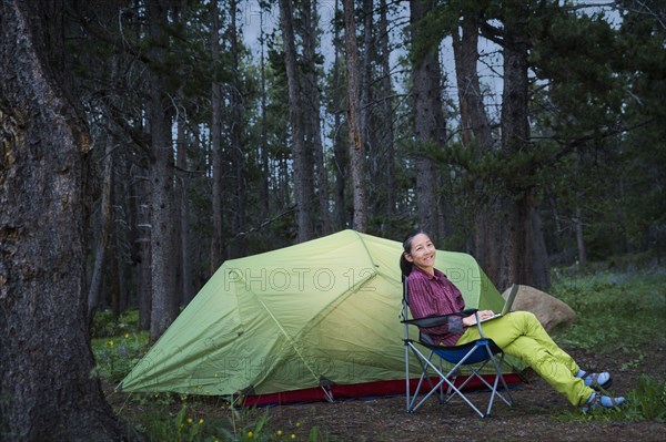 Japanese woman using laptop at campsite