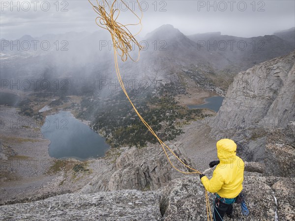 Caucasian climber throwing rope down mountainside
