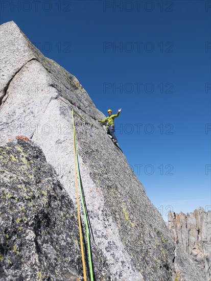 Caucasian climber waving on mountainside