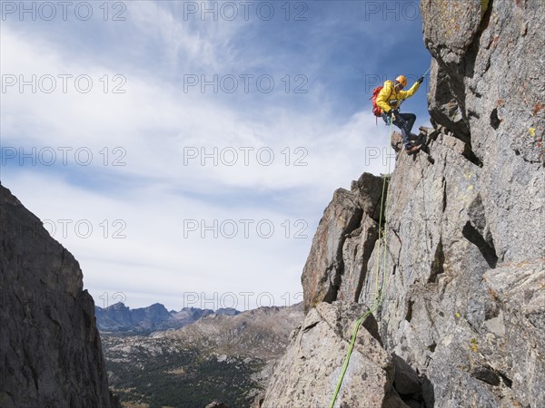 Caucasian climber rappelling on mountainside