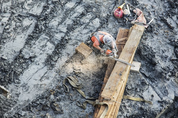 Caucasian worker sawing wood at construction site