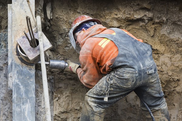 Caucasian worker drilling at construction site