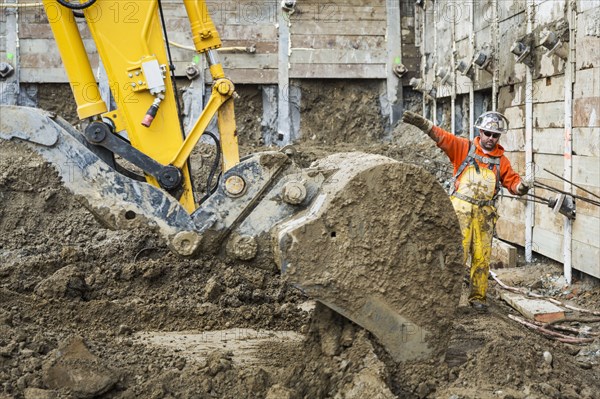 Caucasian worker directing digger at construction site