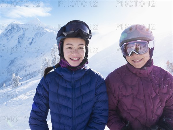 Mother and daughter wearing ski gear on snowy mountain