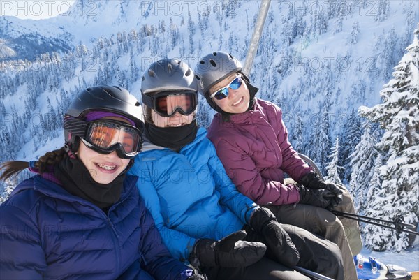 Mother and daughters riding ski lift