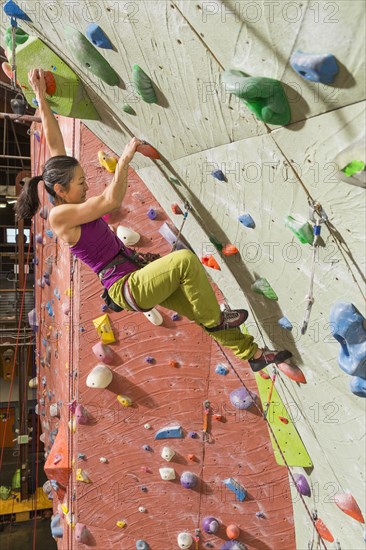Japanese woman climbing rock wall