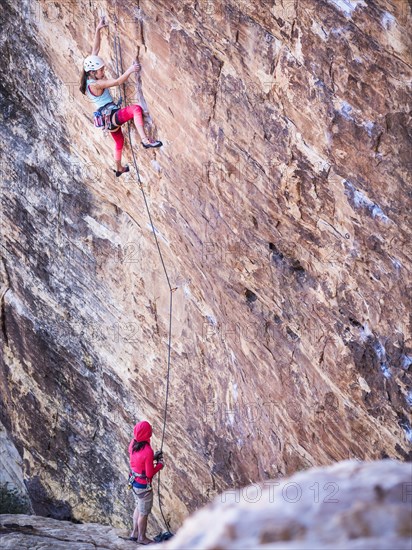 Mother belaying daughter rock climbing on cliff