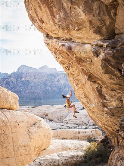 Mixed race girl rock climbing and falling from cliff