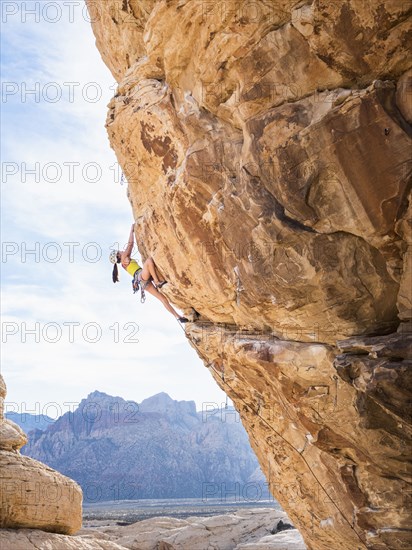 Mixed race girl rock climbing on cliff