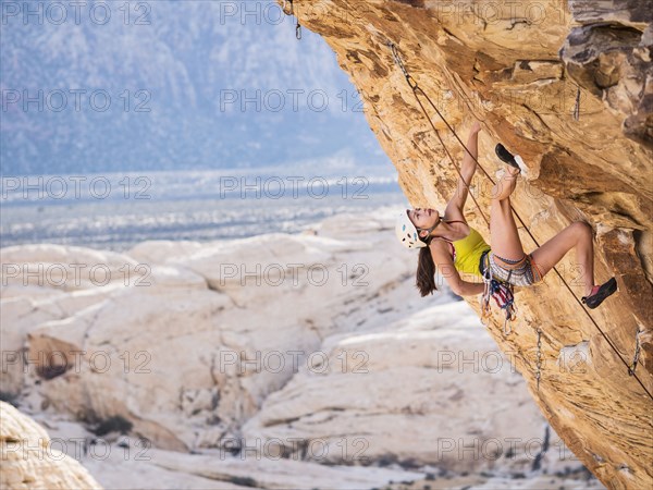 Mixed race girl rock climbing on cliff