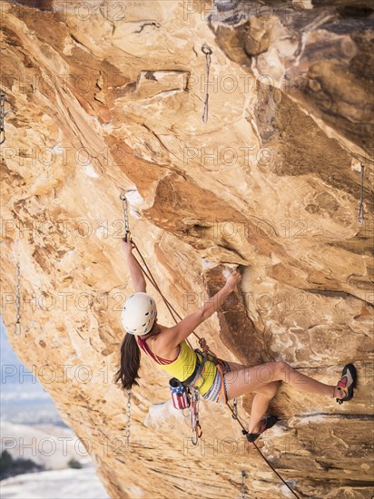 Mixed race girl rock climbing on cliff