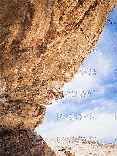 Mixed race girl rock climbing on cliff