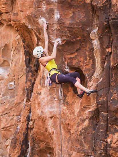 Mixed race girl rock climbing on cliff