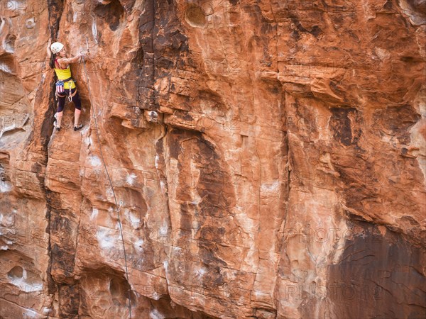 Mixed race girl rock climbing on cliff