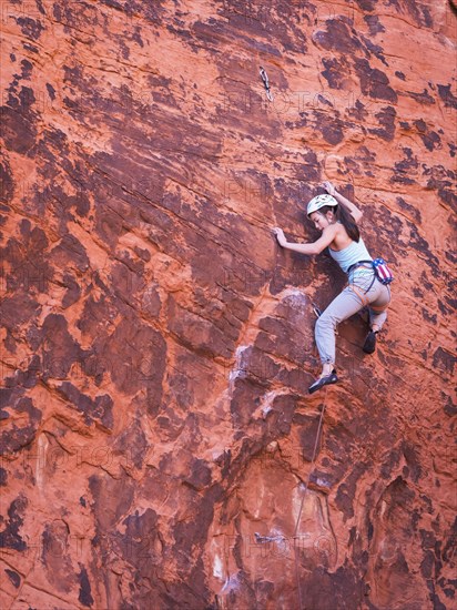 Mixed race girl rock climbing on cliff