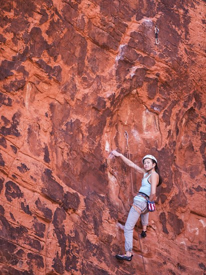 Mixed race girl rock climbing on cliff