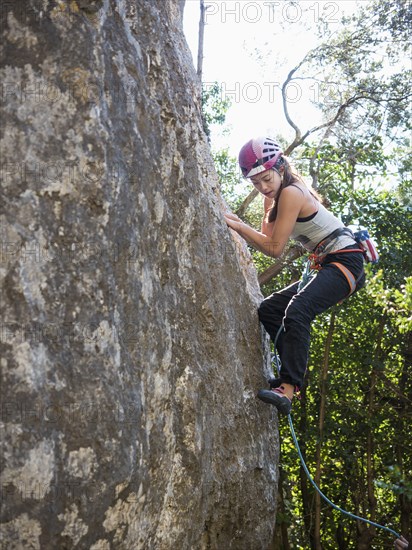 Mixed Race girl climbing rock