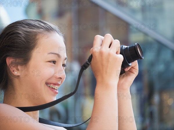 Mixed Race girl photographing outdoors with digital camera